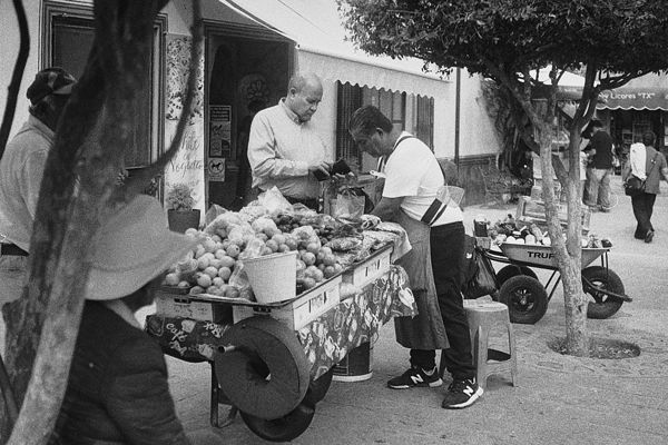 Vendedor de fruta preparando un pedido en su carrito, en la calle